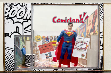 Eine Supermanfigur steht im Schaufenster eines Miniaturmodells eines Comicladens.