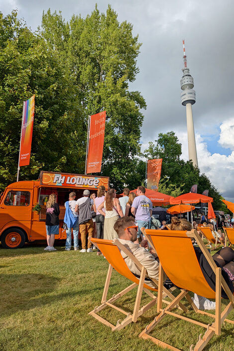 Liegestühle und eine Menschenschlage vor dem FH-Oldtimer HY.