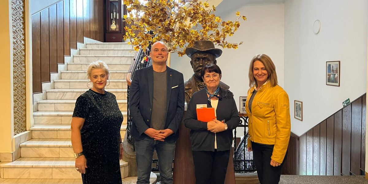 Vier Personen stehen in einem repräsentativen Treppenhaus.