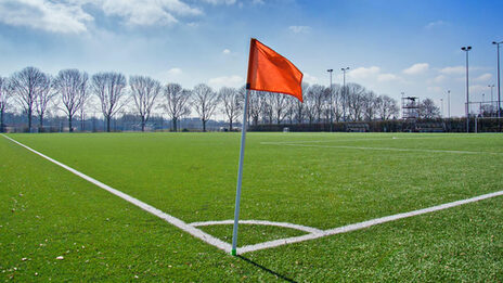 On a soccer field, a corner flag is in the foreground.