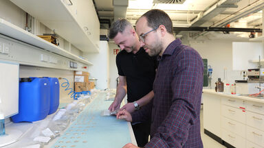 Zwei Personen stehen in einem Labor und untersuchen Proben.
