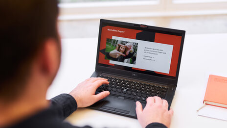 Photo over the shoulder of a man working on a laptop. The slide of a presentation with the title "Any questions left?" is displayed on the laptop.