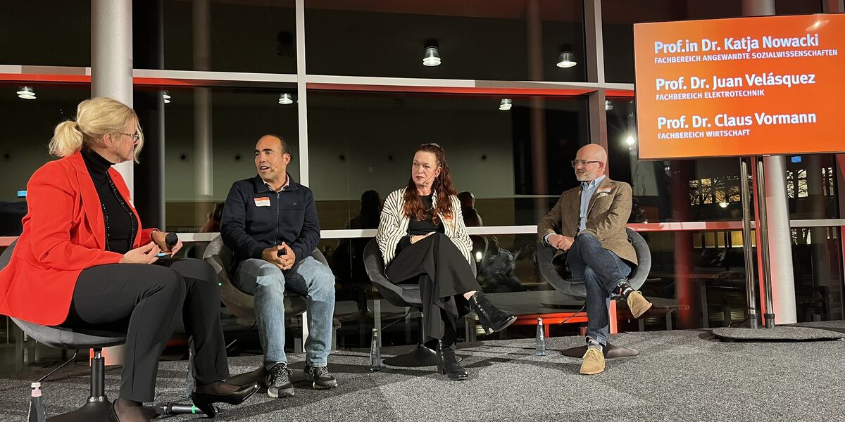 Mehrere Personen sitzen für eine Podiumsdiskussion zusammen.