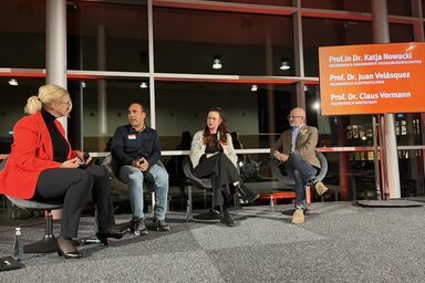 Mehrere Personen sitzen für eine Podiumsdiskussion zusammen.