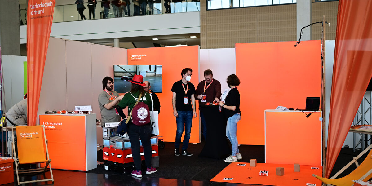 Mehrere Personen sind am Messestand mit verschiedenen Ausstellungsstücken.