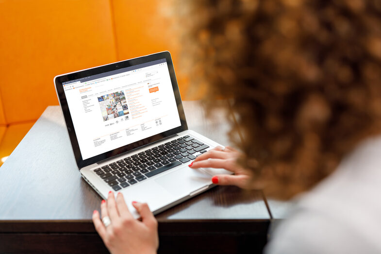 Foto über die Schulter einer Studentin auf einen Laptop, auf dem die Website der Fachhochschule Dortmund aufgerufen ist.__A femal student is sitting and visiting the website of Fachhochschule Dortmund on her laptop.