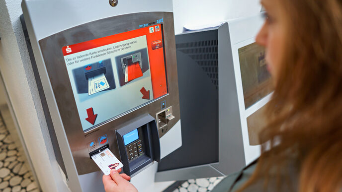 Photo of a student putting her student ID card into the Sparkasse's machine to top up.