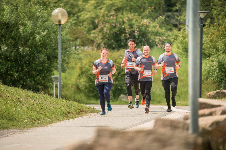 Photo of four employees in FH running gear taking part in an organized run on campus.