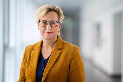 The picture shows the Rector of Fachhochschule Dortmund, Prof. Dr. Tamara Appel. She is standing in a corridor and looking into the camera.